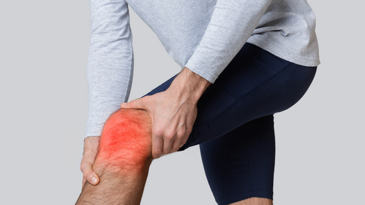 A man holding his inflamed knee, highlighted in red, indicating joint pain and inflammation. The image visually represents conditions like arthritis, which stinging nettle root may help alleviate naturally